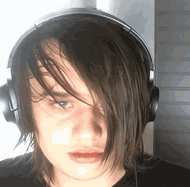 a young man with long hair wearing headphones and a black shirt