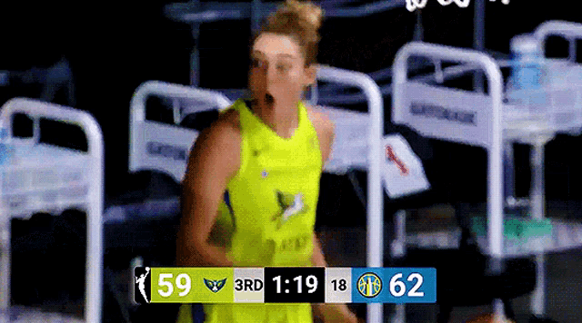 a woman in a yellow jersey stands in front of a scoreboard that says 59 and 62