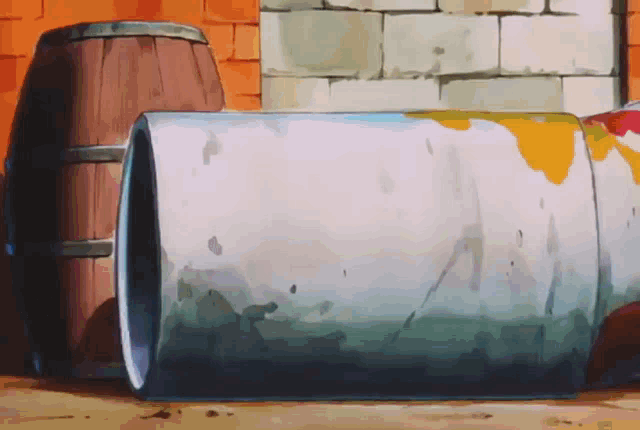 a barrel is sitting in front of a brick wall next to another barrel