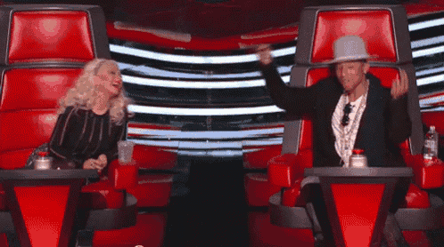a man and a woman are sitting in red chairs and laughing