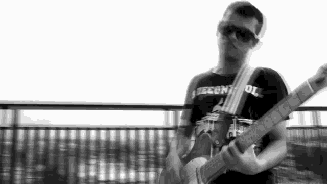 a man playing a guitar with a shirt that says second oil