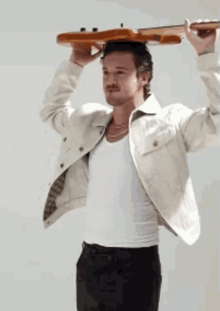 a man in a white jacket is holding a guitar above his head