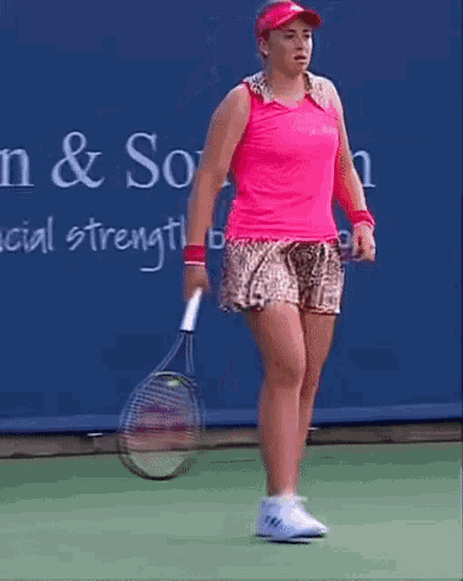 a woman is holding a tennis racquet in front of a sign that says n & so