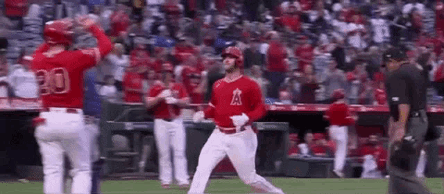 a baseball player is running on the field while a referee looks on .