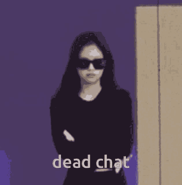 a woman wearing sunglasses and a black shirt is standing with her arms crossed and the words dead chat .