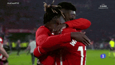 two soccer players hugging each other with the number 11 on their shirts
