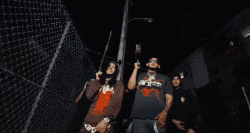 a man with dreadlocks is standing next to a chain link fence and talking on a cell phone