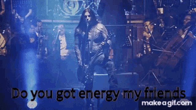 a man with long hair singing into a microphone with the words do you got energy my friends below him