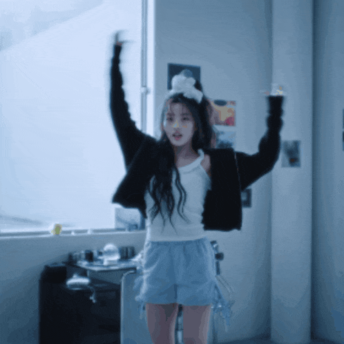 a girl with her arms in the air is wearing shorts and a white tank top