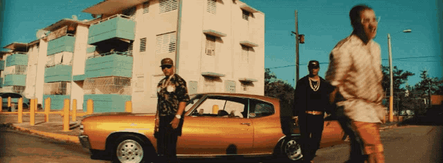 two men are standing next to a yellow car