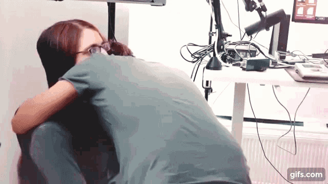 a man and a woman hugging in front of a desk with a computer monitor