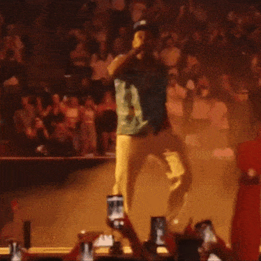 a man is singing into a microphone in front of a crowd of people