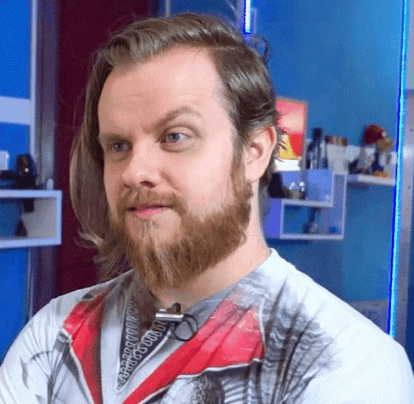 a man with long hair and a beard is wearing a white shirt with a red collar and a microphone on his neck