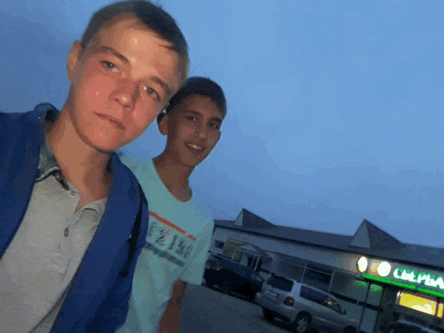 two boys are posing for a picture in front of a store that has the word ultra on the front