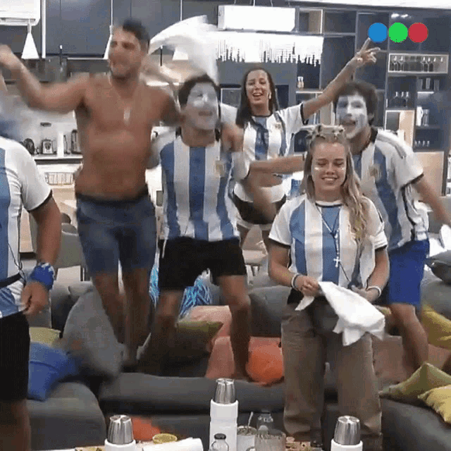 a group of people wearing blue and white striped shirts are dancing in a living room