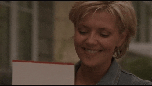 a woman in a blue denim jacket is smiling and holding a piece of paper
