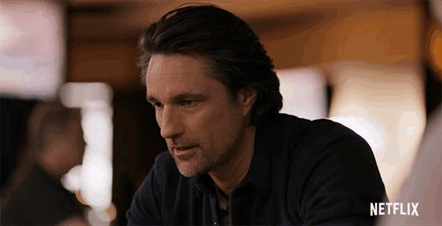 a man sitting at a table with a netflix logo in the background