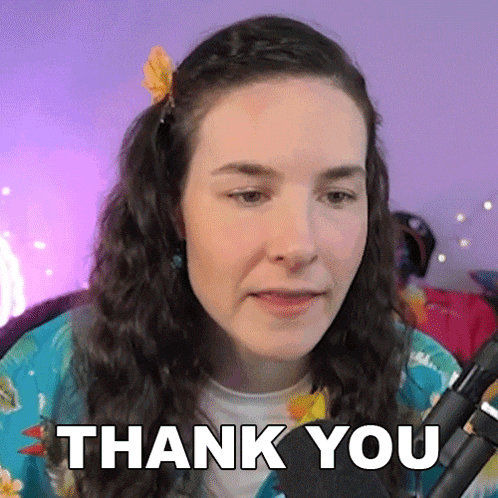 a woman with a flower in her hair is saying thank you in front of a microphone .