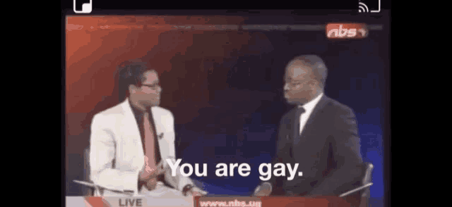 two men are sitting in front of a screen that says ' you are gay '