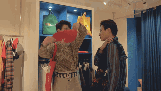 two men are looking at clothes in a store and one has a bag that says leisu