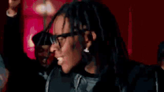 a close up of a person wearing glasses and dreadlocks