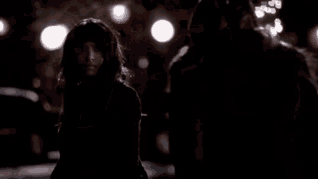 a couple of women are standing in a parking lot at night .