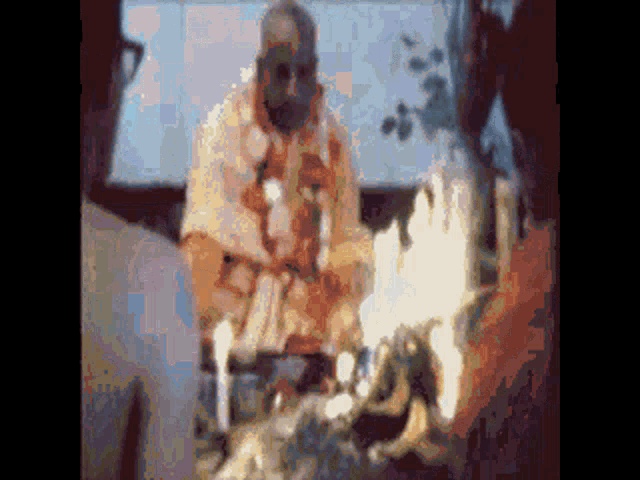 a blurry picture of a man standing in front of a fire with candles