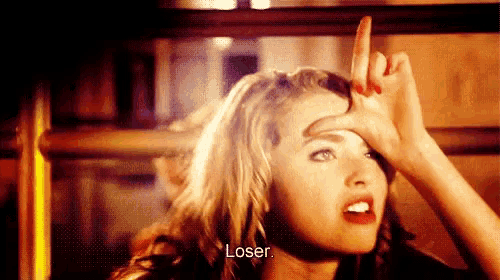 a woman is making a funny face with her hand on her forehead and says `` loser '' .
