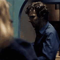 a man in a blue shirt is standing next to a woman in a dark room .