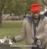 a man wearing a red hat and a jacket is standing in a park with the words `` harlem shake '' written above him .