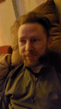 a man with a beard is laying on a bed and smiling