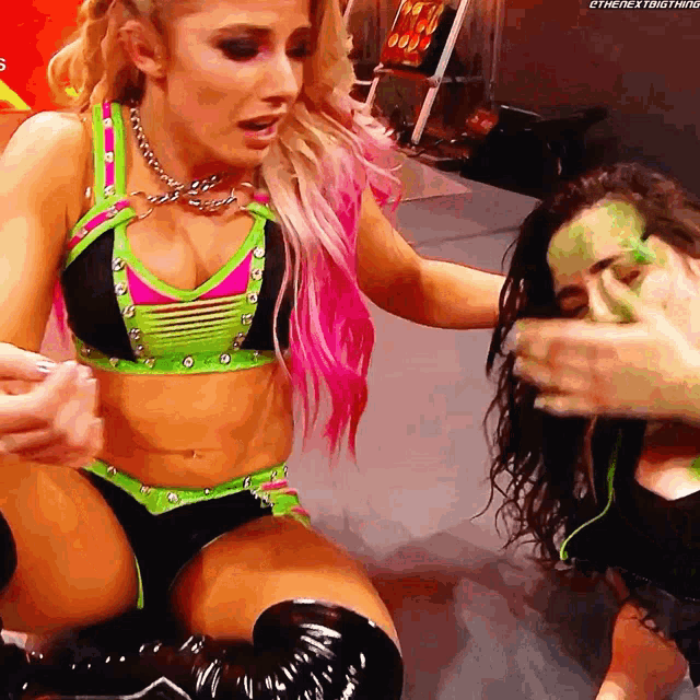 a woman in a green and pink outfit is kneeling down next to another woman