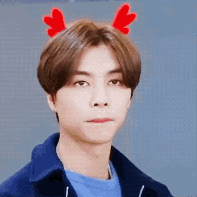 a young man wearing a reindeer headband with his eyes closed and a blue shirt .