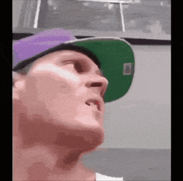 a man wearing a purple hat and a green hat with the letter t on it