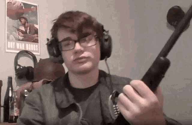 a man wearing headphones and glasses is holding a gun .