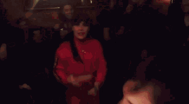 a group of people are dancing in a dark room and a woman is making a funny face .