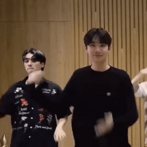 a group of young men are standing next to each other in a room and dancing .