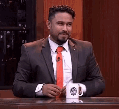a man in a suit and tie is sitting at a table with a cup that says ' lg ' on it .