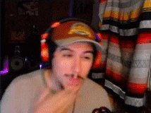 a man wearing headphones and a hat is eating a french fry .