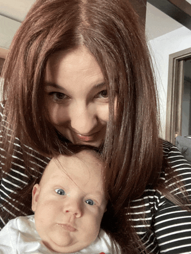 a woman in a striped shirt holds a baby