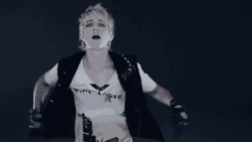 a woman wearing a black vest and a white t-shirt with a bird on it is standing with her hands on her hips