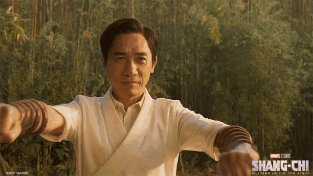 a poster for the movie shang-chi shows a man in a white shirt with his arms outstretched