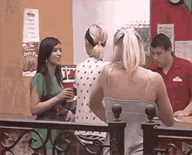 a group of women are standing next to each other in a restaurant talking to a man .