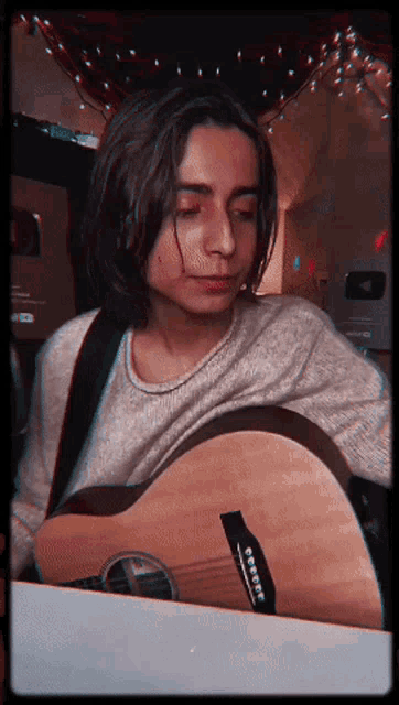 a young man playing an acoustic guitar with a sticker on the neck that says fender