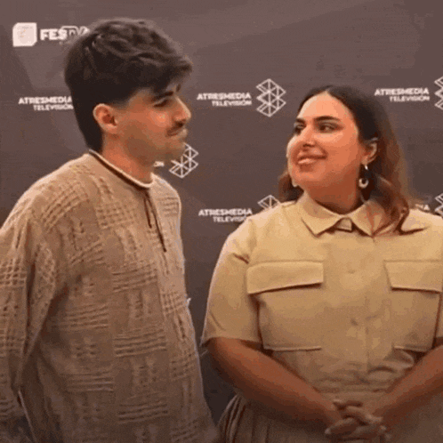 a man and a woman are standing next to each other in front of a wall that says atresmedia television