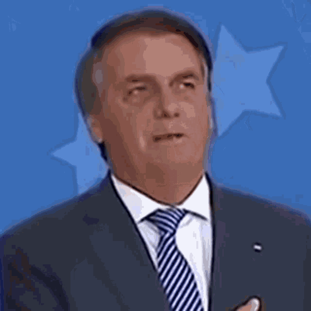 a man in a suit and tie is standing in front of a blue star .