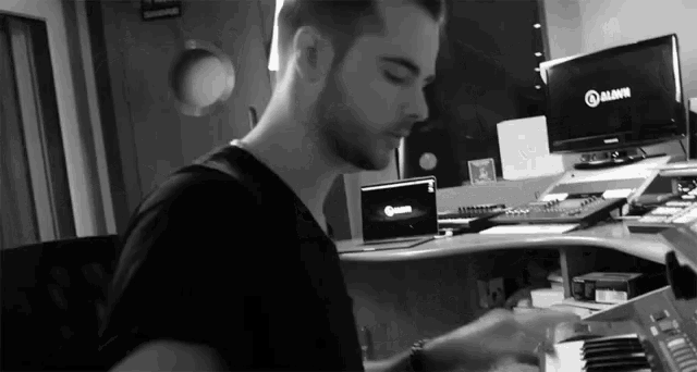 a man in a black shirt is playing a keyboard in front of a monitor that says mavin