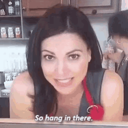 a woman is smiling and saying `` so hang in there '' while sitting in a kitchen .