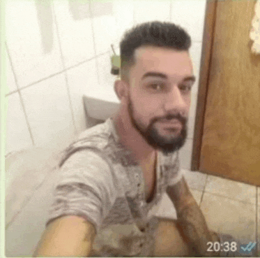 a man with a beard is taking a selfie in a bathroom while sitting on a toilet .