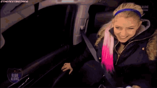 a woman with pink hair is sitting in the back seat of a car ..